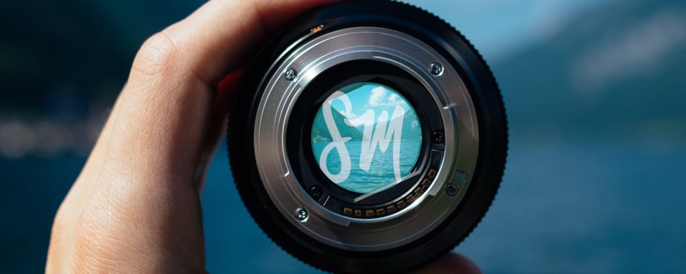 A camera lens being held up by a hand